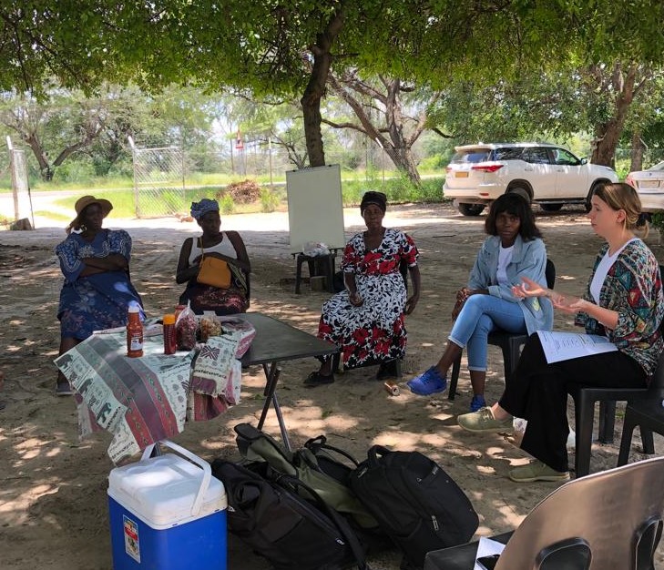 A group of people sitting on chairs in the shade