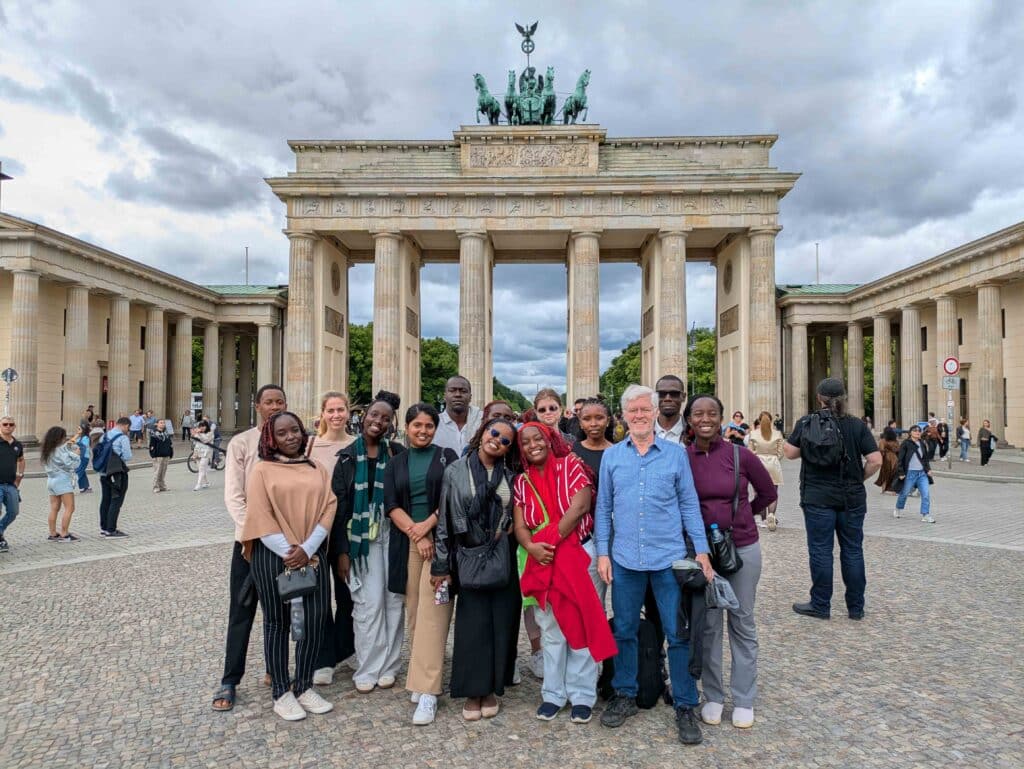 a group of students from kenya and germany in front of the brandenburg gate in berlin