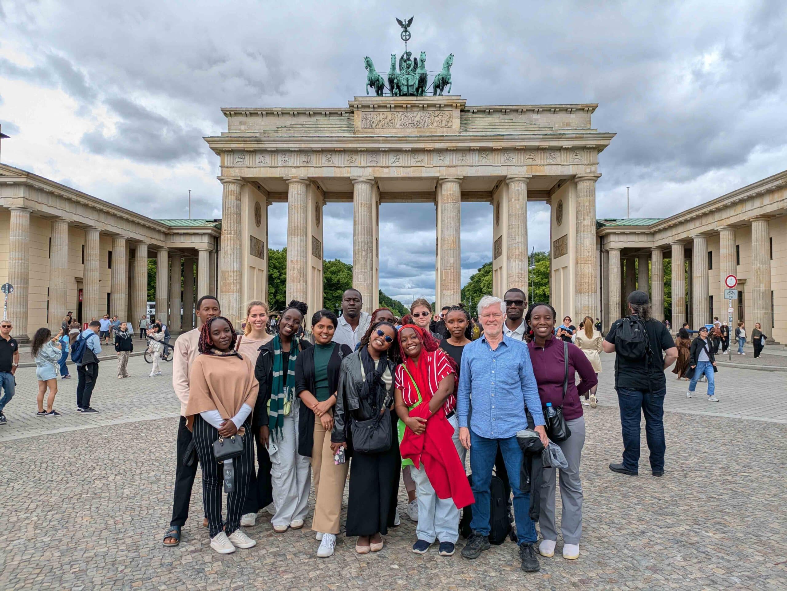 a group of students from kenya and germany in front of the brandenburg gate in berlin