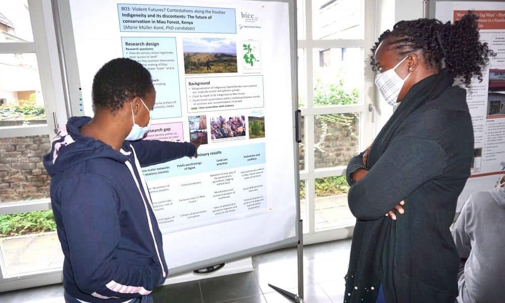 two scientists standing in front of poster